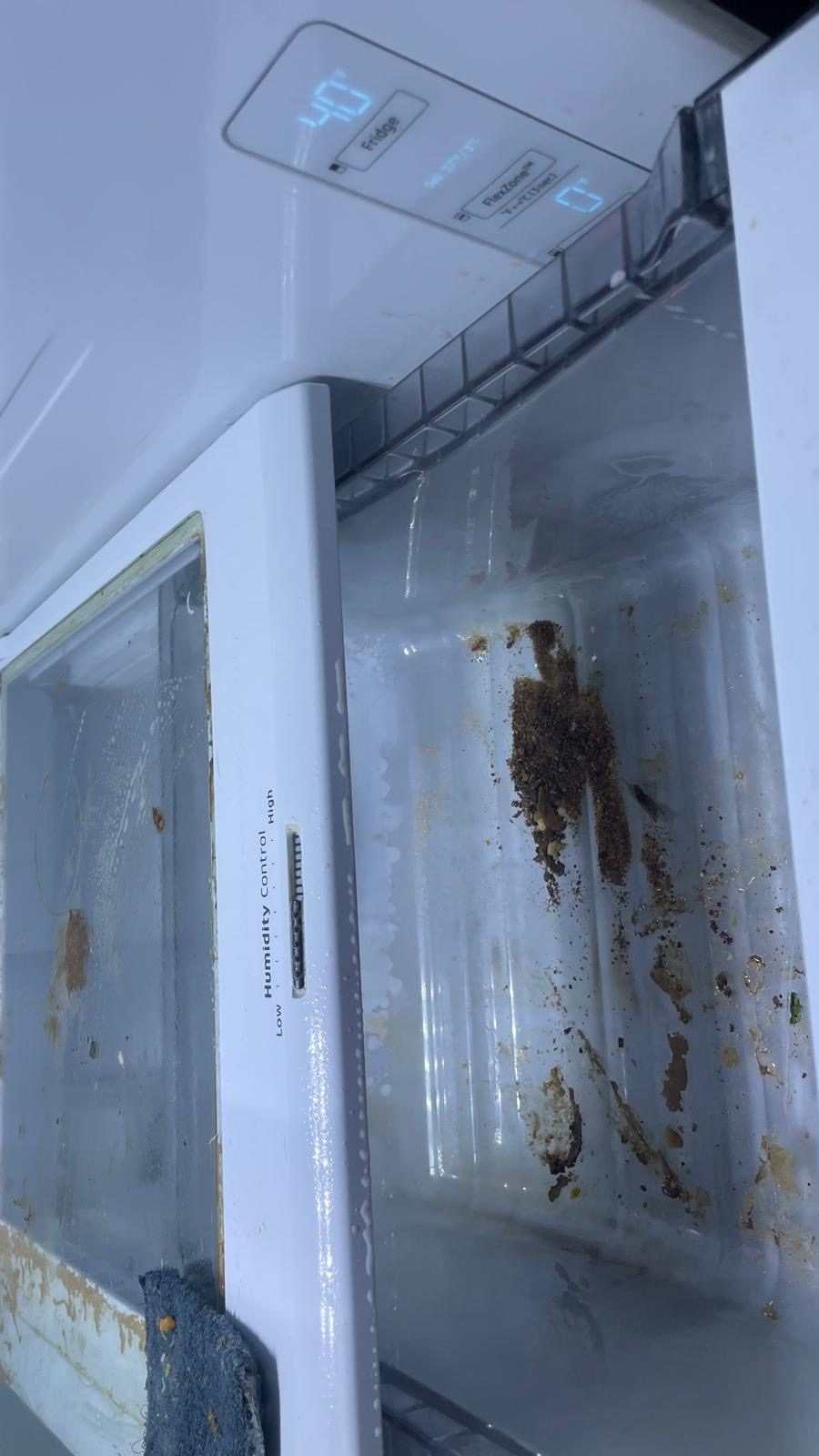 Refrigerator drawers and shelves with dried food debris before cleaning.